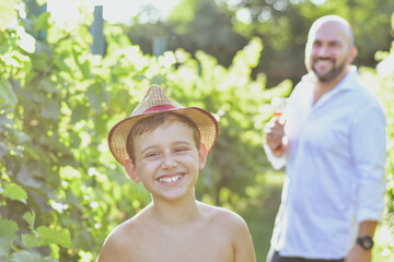 Fototapeta premium Father and Son in Vineyard.Beautiful smiling bearded father with white shirt and his cute son having Fun at a vineyard.