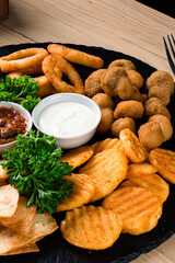 Deef Fried Fresh Beer Plate with Chicken Nuggets, Cheese Fingers, Onion Rings, Sauce on wood table.