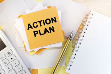 the action plan is written on a stack of note sheets. A notepad and a pen with a white calculator. Business concept