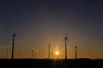 Windräder bei Sonnenuntergang auf einem Feld produzieren Strom	