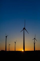 Windräder bei Sonnenuntergang auf einem Feld produzieren Strom	
