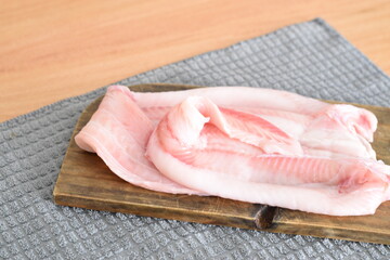 some hake fillets on a wooden board on the table