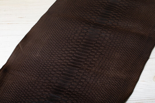 Brown dyed folded natural genuine python leather on the wooden table