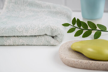 Bathroom table surface with organic olive soap on tray and fresh towel. Personal hygiene and health care concept