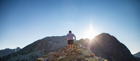 trail runner running in mountain landscape at sunset active lifestyle