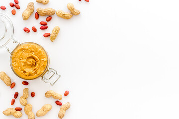 Bowl of peanut butter with nuts on kitchen table. Overhead view