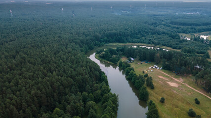 Aerial drone view of big tent between trees in evening forest on riverbank. Adventure concept.