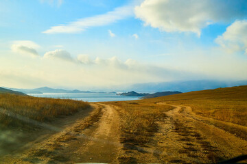 Nature landscape with golden glass, old rural road, hills and blue sky with white clouds on background in a nice day or a evening