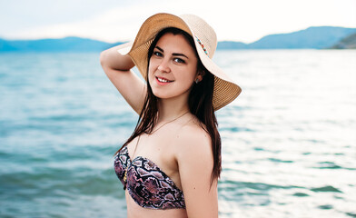Portrait of a woman in a straw hat on the beach. Happy beautiful girl close-up, hair fluttering in the wind. Portrait of a young smiling woman in the open air. ocean.