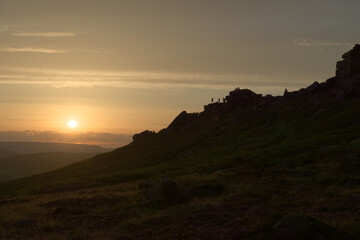 Wide angle sunset at stanage edge. Many people pursue outdoor recreational activities on top of the rocky edge. Dramatic and popular landmark