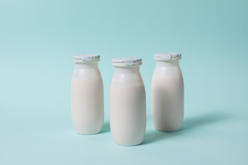 Bottles with probiotics and prebiotics dairy drink on light blue background.