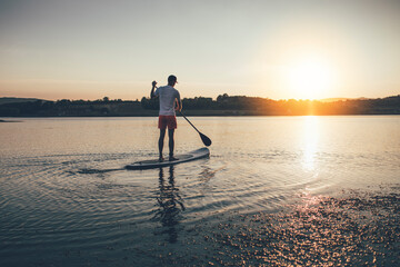 Man floating on the lake on paddle board, copy space