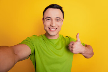 Portrait of cheerful guy raise thumb up shoot selfie on yellow background