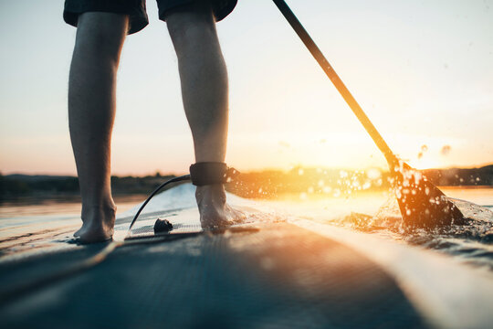 Close up of man paddleboarding at sunset