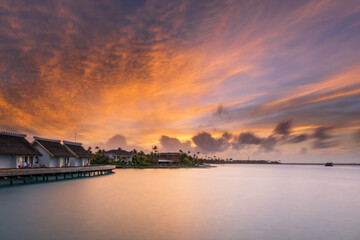 Fototapeta premium Sunset over sand island beach in Maldives. Crossroads Maldives islands. Long exposure picture taken in july 2021