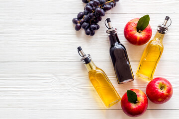 Apple cider and balsamic vinegar in bottles with grapes and red apples