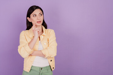 Portrait of doubtful pensive woman look up empty space think finger chin on violet background