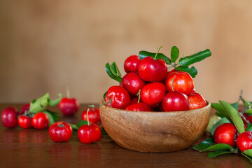Acerola Cherry in wooden bowl on wooden table with rustic brown background.