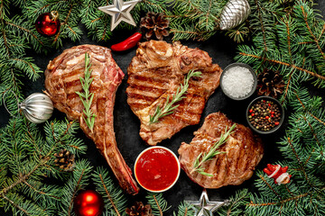 A variety of grilled Christmas beef steaks. Ribeye steak, tomahawk, T-bone, with Christmas tree and...