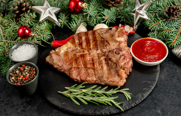 Grilled Christmas T-bone steak with tree and decorations on stone background 
