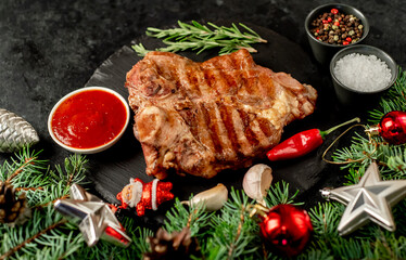 Grilled Christmas T-bone steak with tree and decorations on stone background 