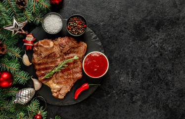 Grilled Christmas T-bone steak with tree and decorations on stone background with copy space for your text