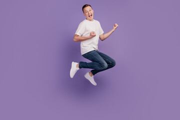 Portrait of cheerful astonished guy jump winner concept on violet background