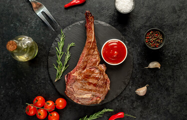 grilled Tomahawk steak with spices on a stone background