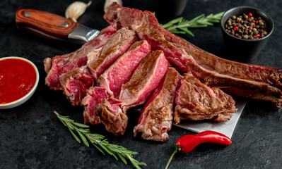 grilled Tomahawk steak, on a knife with spices on a stone background