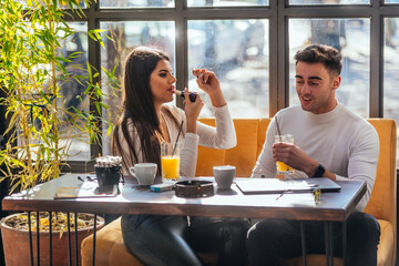 Two happy young couple sitting at a table in indoor cafe