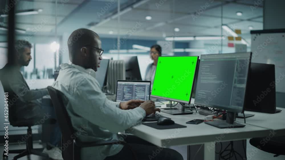 Poster Multi-Ethnic Office: Black IT Programmer Working on Computer with Green Screen Chroma Key Display. Male Software Engineer Developing App, Program, Video Game. Terminal with Code Language. Static Shot