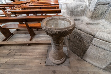 Classic baptismal font, made of a stone of granite, used for baptism in a european catholic church