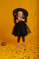 beautiful happy little blonde girl in a black dress black hat red tights with black stripes tinsel halloween holiday
