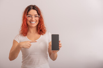 Naklejka premium A Caucasian woman points to a smartphone with a blank screen on a white background