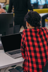 Picture from behind of a female employee sitting at her desk and working on her laptop