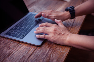 Closeup photo of male hands with laptop, businessman working at cafe.