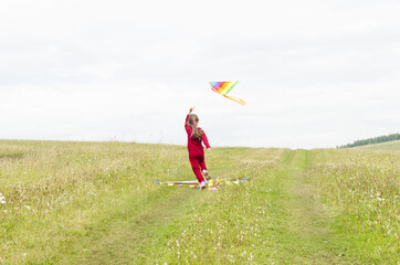 A child running with a kite on the background of grass and sky. A child with a kite