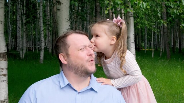 sweet little daughter, 3 years old, tells her daddy in her ear and laughs. The concept of a happy childhood, fatherhood, parenting. A trusting relationship between parents and children. Fathers day