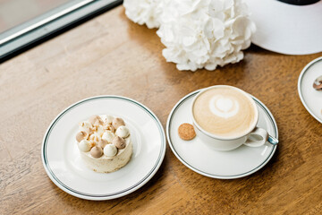 delicious dessert and a cup of coffee on the table. Enjoy a freshly baked dessert in a coffee shop, restaurant. A closeup shot of a little sweet decorative cake and a cappuccino. Soft selective focus.