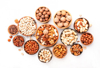 Nuts in bowls. Almonds, hazelnuts, walnuts and other. Healthy food snack mix on white table, top view, copy space