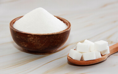 white granulated and sugar pieces in a wooden spoon