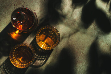 American bourbon whiskey in glasses and bottle, rusty green background with shadow pattern and negative space