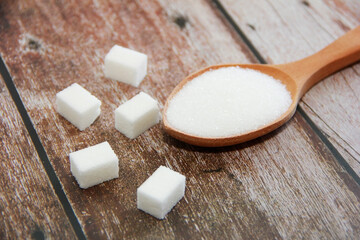 white granulated and sugar pieces in a wooden spoon