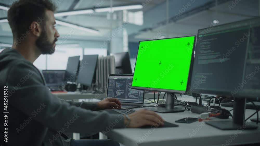 Fototapete Multi-Ethnic Office: White IT Programmer Working on Computer with Green Screen Chroma Key Display. Male Software Engineer Developing App, Program, Video Game. Terminal with Code Language. Static Shot