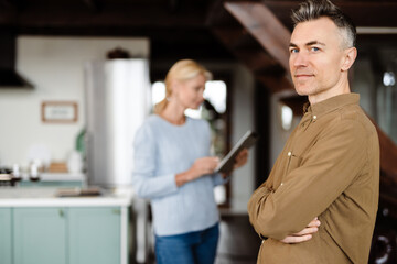 Smiling mid aged man standing at the living room