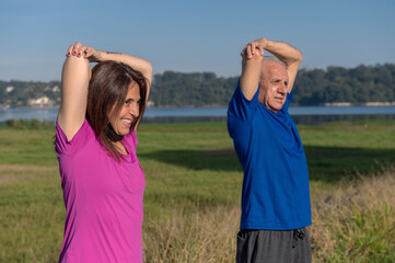 young woman and senior man stretching in a park on a sunny day