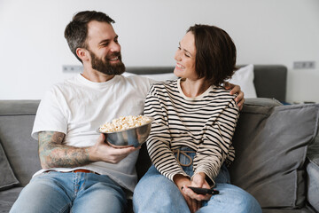 Happy young white couple watching TV