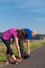 young woman and senior man stretching in a park on a sunny day