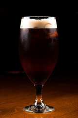 Ice cold glass of dark beer with foam. Stout beer freshly poured
