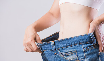 Close up slim woman measuring her thin waist. Healthcare and woman diet lifestyle concept to reduce...